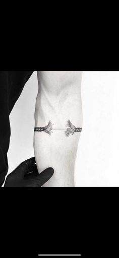 an arrow tattoo on the side of a person's leg, with two hands holding it