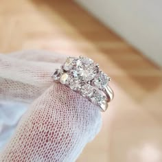 a close up of a person's hand holding a ring with three diamonds on it