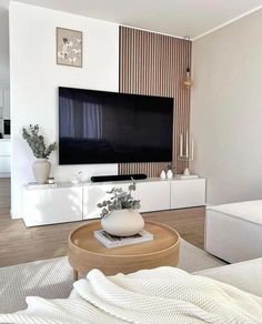 a living room with a large flat screen tv mounted on the wall above a wooden coffee table