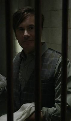 a man standing behind bars in a jail cell