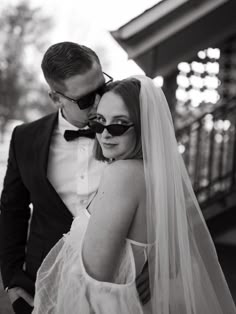 a bride and groom pose for a black and white photo in front of a building