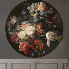 a large round painting with flowers on the wall in front of a chair and lamp