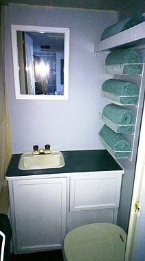 a small bathroom with white cabinets and green towels on the shelf next to the sink