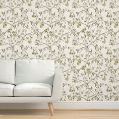 a white couch sitting in front of a wallpapered with green leaves and flowers