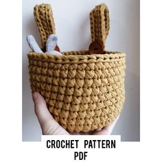 the crochet pattern has two bunny ears on it and is in a basket