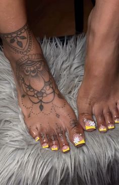 a woman's feet with yellow and white nail polishes on top of it