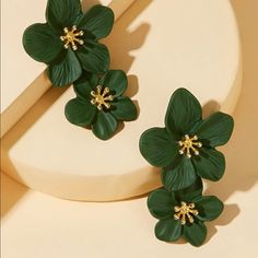 two green flower earrings sitting on top of a table