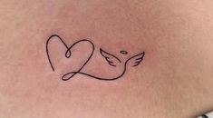 a woman's stomach with a small tattoo on the side of her stomach and a heart in the shape of a dove