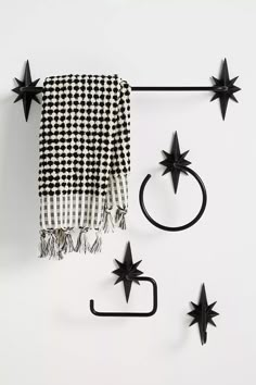 three black stars hang on the wall next to a towel rack and two rings with hooks