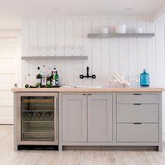 a kitchen with white walls and wood flooring has an ice chest in the center