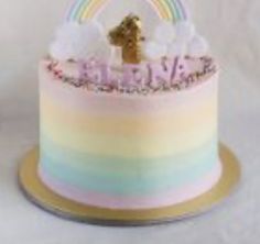 there is a cake that has a rainbow design on the top and a gold cross on the bottom