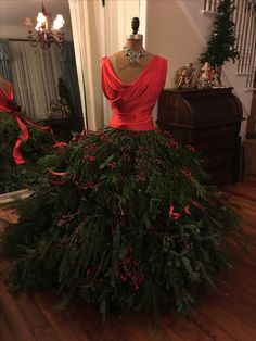 a dress made out of evergreen leaves and red berries is on display in the foyer