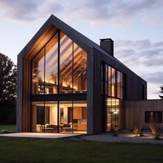 a modern house with glass walls and wood trimmings on the outside, surrounded by grass