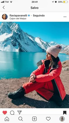 a woman sitting on top of a mountain next to a lake and snow covered mountains