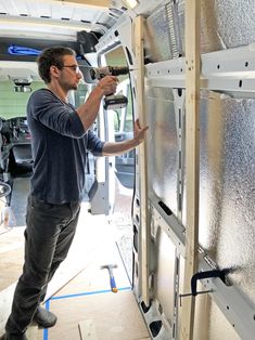 a man is working on the side of a van with its door open and tools in his hand