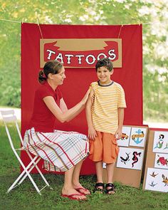 a little boy and woman standing in front of a tattoo booth