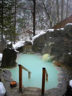 a blue pool surrounded by snow covered rocks