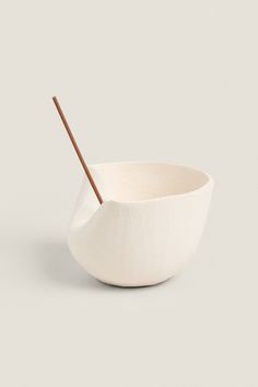 a white bowl with a wooden stick sticking out of it