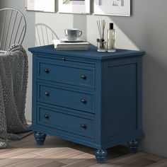 a blue chest of drawers next to a chair and table with pictures on the wall