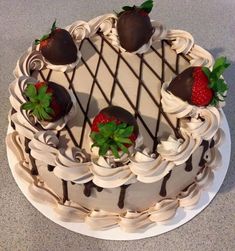 a white cake with chocolate covered strawberries on top and green leaves in the middle