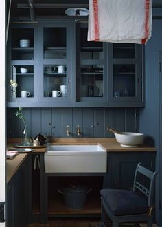 a kitchen with blue walls and wooden floors, an old fashioned sink in the center