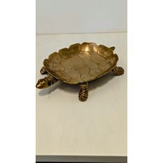 a brass turtle shaped dish on a white surface