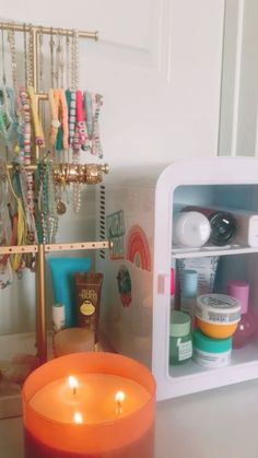 an orange candle sitting on top of a table next to a small cabinet filled with jewelry