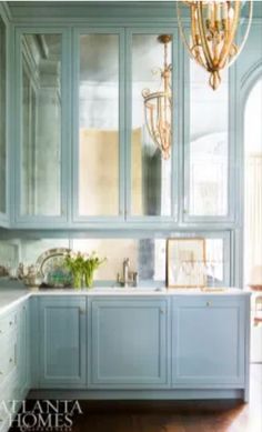 a kitchen with blue cabinets and chandelier hanging from it's side wall