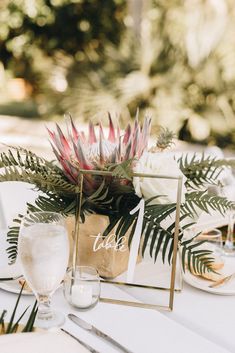 a table topped with a vase filled with flowers and greenery