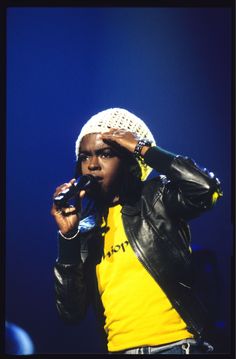 a man holding a microphone in his right hand and wearing a hat on top of his head