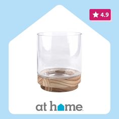 a clear glass with wooden coasters in front of a blue background and the words at home on it