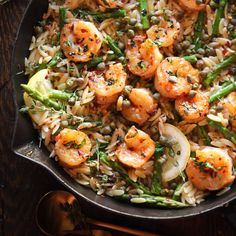 shrimp and asparagus stir fry in a skillet on a white tablecloth