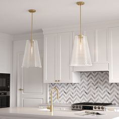 two lights hanging over a kitchen island in a white and gold colored kitchen with herringbone backsplash