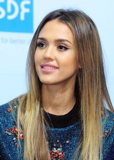 a close up of a person with long hair wearing a blue sweater and black shirt