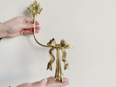 two hands are holding a gold colored metal key with a bow on the end, and another hand is reaching for it