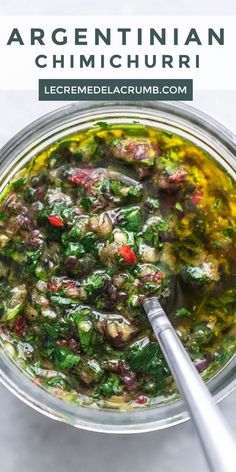 a glass bowl filled with greens and meats next to a spoon on top of a table