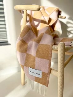 a pink and brown checkered blanket sitting on top of a wooden chair