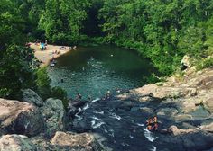 people are swimming in the river surrounded by rocks