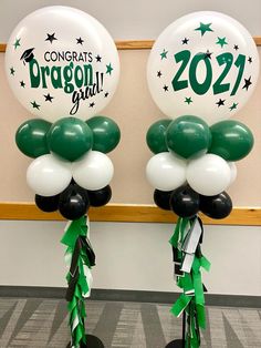 two balloons with green and white streamers are in front of a wall that says congrats dragon ball grad