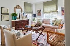 a living room filled with lots of furniture next to a wall covered in pictures and paintings