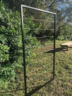 a metal fence is in the middle of a grassy area with trees and benches behind it