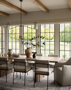 the dining room table is surrounded by chairs and vases with flowers in them,