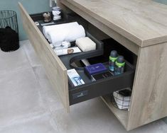 an open drawer in a bathroom with toiletries and personal care items on the counter