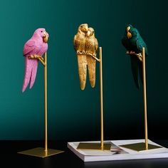 three parrots are perched on gold perches