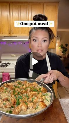 a woman with an apron on holding a pan of food in front of her face