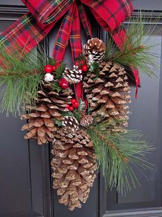 a wreath with pine cones and berries hanging on a door