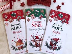 three christmas gift tags on a white surface with red and green decorations around them, one for joyeux noel