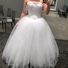 a woman taking a selfie in a wedding dress with her cell phone up to her ear