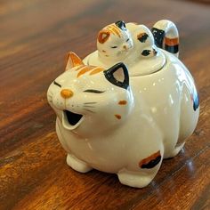 two ceramic cats sitting on top of a wooden table