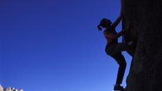 a woman climbing up the side of a mountain